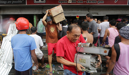 Người dân Tacloban mang đồ lấy cắp ra khỏi một cửa hàng.